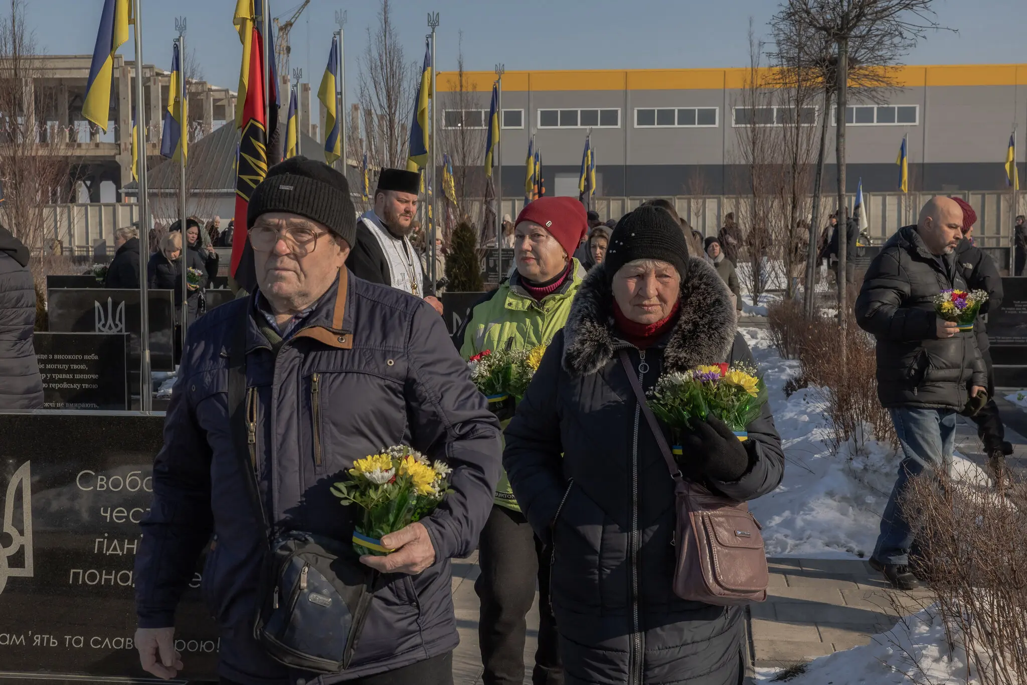 Люди несуть квіти до могил українських воїнів на панахиді в Бучі, Україна, у понеділок.